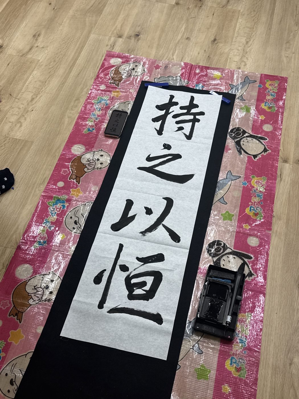 完成した『持之以恒』の一枚が、机のそばで背中を押す。